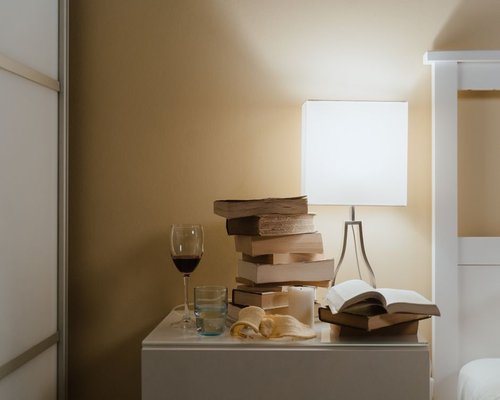 Nightstand with a warm glowing lamp, a physical book, and a tablet resting quietly